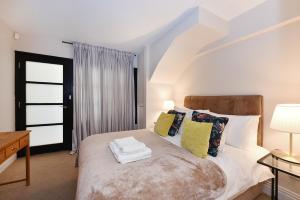 a bedroom with a large bed with yellow pillows at London Choice Apartments - South Kensington - Mews House II in London