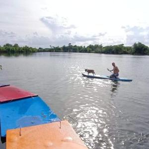 a man and a dog on a boat in the water at Kram Farmstay in Nakhon Pathom