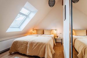 two beds in a attic bedroom with a window at Apartments Kassebohmer Weg in Rostock