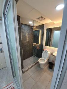 a bathroom with a toilet and a glass shower at Burgundy McKinley Place Service Apartment in Manila