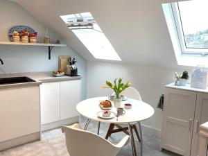 een keuken met een witte tafel en stoelen bij The Seawitch - harbourside apartment in Mousehole