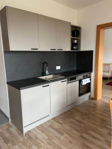 eine Küche mit weißen Schränken und einer schwarzen Arbeitsplatte in der Unterkunft Family XL - Ferienwohnungen in Lutzmannsburg