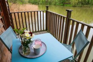 a table with a vase of flowers on a deck at Lakeside Cabin on Stilts- 'Kingfisher' in Rous Lench