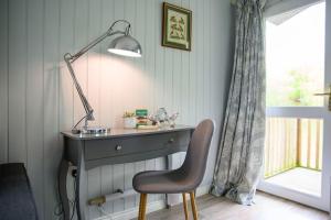 a desk with a lamp and a chair next to a window at Lakeside Cabin on Stilts- 'Kingfisher' in Rous Lench