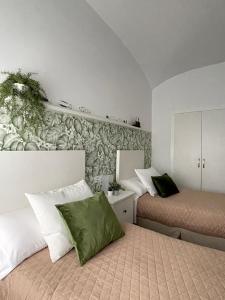 Un dormitorio con 2 camas y una pared con plantas. en Casa Rural LA CASA DEL AGUA MÉRIDA, en La Garrovilla