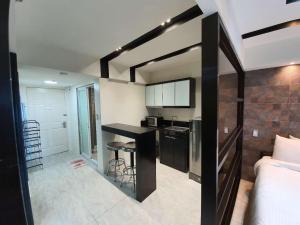a room with a kitchen and a bedroom with a bed at Burgundy McKinley Place Service Apartment in Manila
