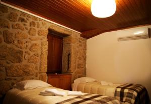 two beds in a room with a stone wall at Cantinho Santiago in Belmonte
