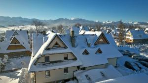 un techo cubierto de nieve de una casa en Pokoje Gościnne Stoch, en Ząb