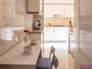a white kitchen with two cups on a table at Carabela 1º3ª in Sant Feliu de Guíxols