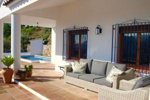 - un salon avec un canapé et une piscine dans l'établissement Casa El Boqueron:rust en relaxen met een prachtig uitzicht!, à Cómpeta