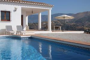 une villa avec une piscine en face d'une maison dans l'établissement Casa El Boqueron:rust en relaxen met een prachtig uitzicht!, à Cómpeta