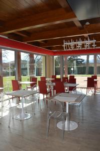 un comedor con mesas, sillas y ventanas en Suite Testani, en Frosinone