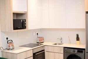 eine weiße Küche mit einer Spüle und einer Mikrowelle in der Unterkunft Precious Paradise Zimbali Blvd in Ballito
