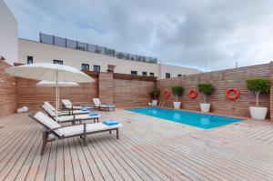 un patio con sillas, una sombrilla y una piscina en Hotel Ceuta Puerta de Africa en Ceuta