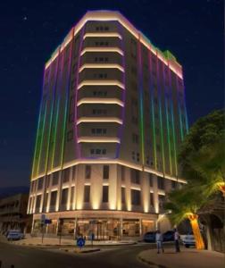 The Saj Hotel في عجمان: مبنى كبير عليه انارة خضراء وارجوانية