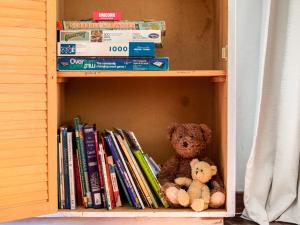 uma estante de livros com um urso de peluche e livros em Kereru Cottage - Pohara Holiday Home em Pohara