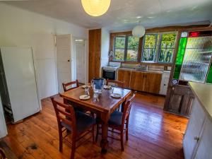 uma mesa de jantar com cadeiras e uma cozinha em Kereru Cottage - Pohara Holiday Home em Pohara