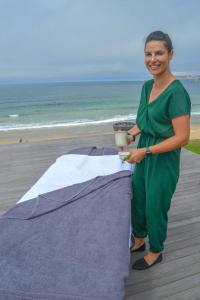 a woman standing next to a table on the beach at African Oceans Manor on the Beach in Mossel Bay