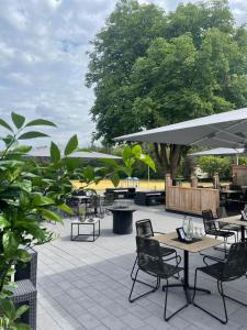 eine Terrasse mit Tischen, Stühlen und einem Baum in der Unterkunft Hotel Gasthof zum Wulfen in Sulzbach-Rosenberg
