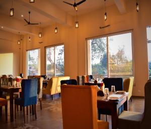 una sala da pranzo con tavoli, sedie e finestre di Kumbhal Exotica Resort Kumbhalgarh a Kumbhalgarh