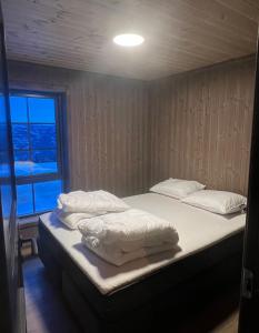 um quarto com 2 camas com lençóis brancos e uma janela em Ski in/ski out i Aurdal - helt ny hytte em Aurdal