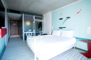 ル・テュケ・パリ・プラージュにあるIbis Styles Le Touquetの白いベッドと青い壁が備わるベッドルーム1室が備わります。