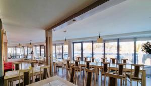a restaurant with wooden tables and chairs and large windows at Hotel Mare & Restaurant in Roja
