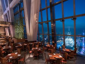 um restaurante com mesas e cadeiras e vista para a cidade em Park Hyatt Shanghai em Xangai