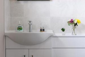 un bagno bianco con lavandino e fiori di Crannog Cottage a Llandudno