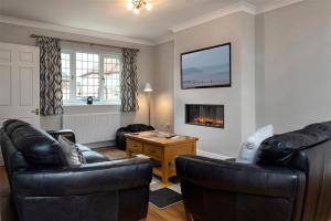 a living room with two leather chairs and a fireplace at Crannog Cottage in Llandudno