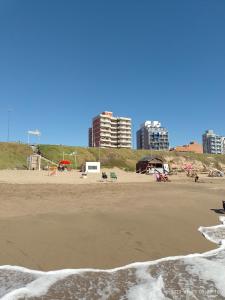 uma praia arenosa com edifícios ao fundo em Departamento frente al Mar. em Mar del Plata