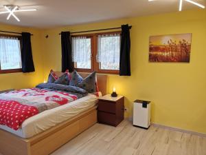 a bedroom with yellow walls and a bed with a night stand at Studio mit traumhafter Aussicht in Ritzingen