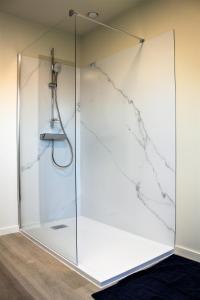 um chuveiro com uma porta de vidro e uma parede de mármore em Bibi's Boerderij em Veurne