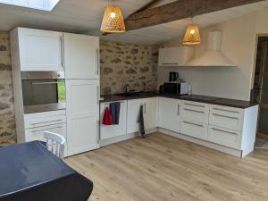 a kitchen with white cabinets and a counter top at Maison de Vacances 12min du Puy du fou grand studio in Saint-Laurent-sur-Sèvre