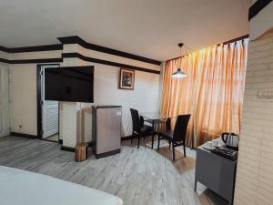 a hotel room with a dining table and a television at Hotel De Khuvieng in Chiang Mai