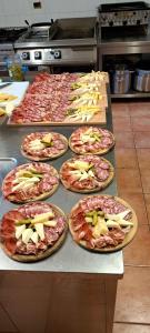 een rij pizza's op een tafel in een keuken bij El Malget in Tuenno
