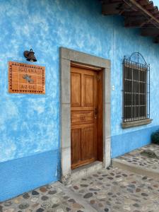 niebieski budynek z drewnianymi drzwiami i zegarem w obiekcie Hostel Iguana Azul w mieście Copán