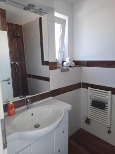 W łazience znajduje się biała umywalka i lustro. w obiekcie Villa Mariensiel 1OG li w mieście Sande