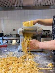 een persoon die een pastamachine gebruikt in een keuken bij El Malget in Tuenno