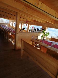 een restaurant met houten tafels en stoelen en wijnflessen bij El Malget in Tuenno