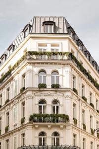 Un grand bâtiment blanc avec des fenêtres et des plantes dans l'établissement Château des Fleurs - Hôtel & Spa - Paris Champs-Elysées, à Paris