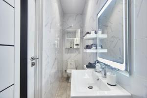 W białej łazience znajduje się umywalka i lustro. w obiekcie Apartments Club Marine w Odessie