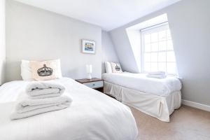 2 camas blancas en una habitación con ventana en Cozy and Spacious Kensington Maisonette en Londres