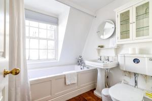 a bathroom with a sink and a toilet and a window at Cozy and Spacious Kensington Maisonette in London
