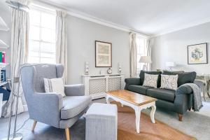 sala de estar con 2 sillas, sofá y mesa en Cozy and Spacious Kensington Maisonette en Londres