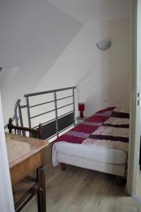 een slaapkamer met een bed en een houten tafel bij Gîtes Bellevue et Mascaret in Courtils