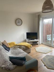 uma sala de estar com um sofá e um relógio na parede em Home from Home sleeps seven em Hastings