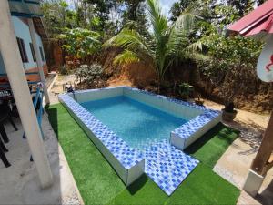 a swimming pool with blue tiles on the grass at Man Homestay in Kampong Bukit China