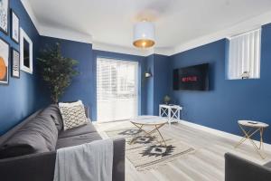 a living room with blue walls and a couch at Homebird Property - The Willows in Leeds
