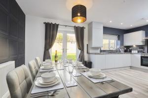a dining room table with chairs and a kitchen at Homebird Property - The Willows in Leeds